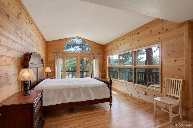 13190 Coyote Song Trl, Conifer, CO 80433 - bedroom with wood walls, lofted ceiling, access to exterior, light wood-type flooring, and french doors