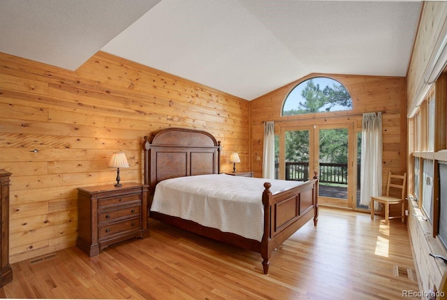 13190 Coyote Song Trl, Conifer, CO 80433 - bedroom featuring lofted ceiling, wooden walls, access to outside, light wood-type flooring, and french doors
