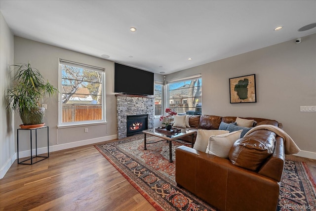 living room with a stone fireplace and hardwood / wood-style floors