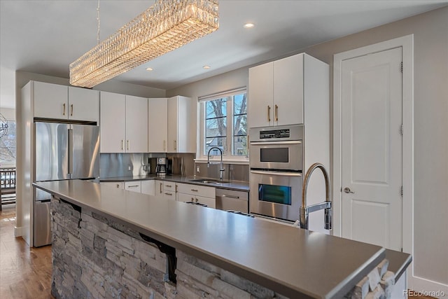 kitchen featuring tasteful backsplash, decorative light fixtures, sink, and white cabinets