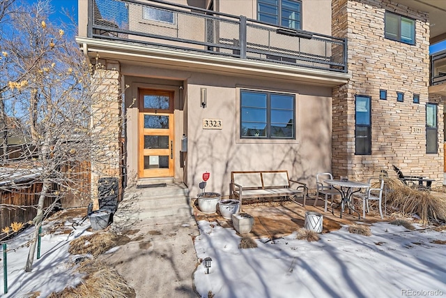 snow covered property entrance with a balcony