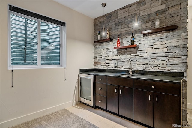 bar featuring dark brown cabinetry, sink, wine cooler, and a wealth of natural light