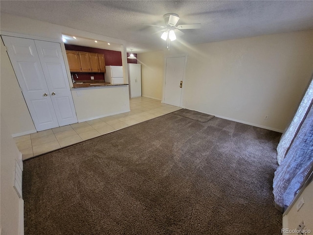 unfurnished living room featuring light colored carpet, light tile patterned flooring, ceiling fan, a textured ceiling, and baseboards