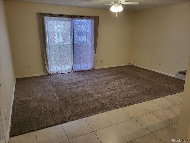 carpeted empty room with tile patterned flooring, a ceiling fan, and baseboards