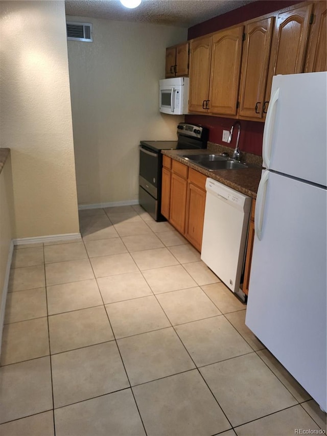 kitchen with white appliances, visible vents, a sink, and light tile patterned flooring