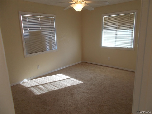 carpeted empty room with ceiling fan and baseboards