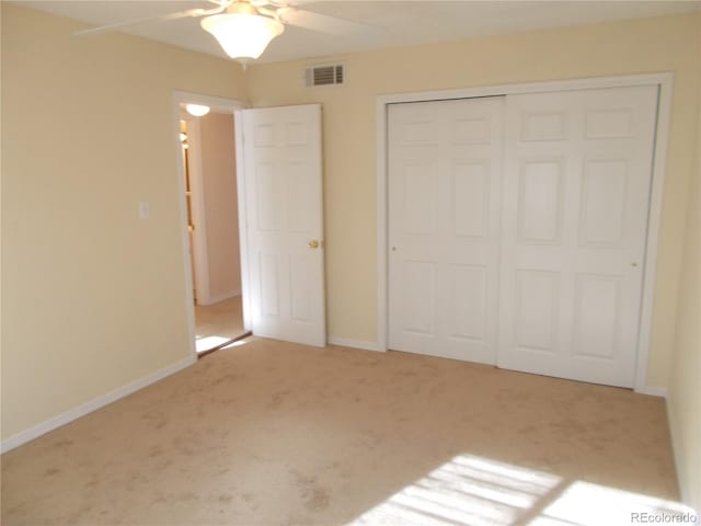 unfurnished bedroom with a closet, light colored carpet, visible vents, ceiling fan, and baseboards