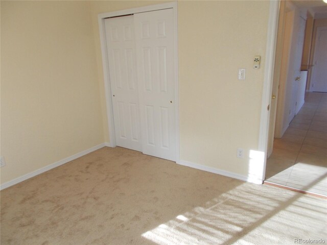 unfurnished bedroom featuring carpet floors, a closet, tile patterned floors, and baseboards