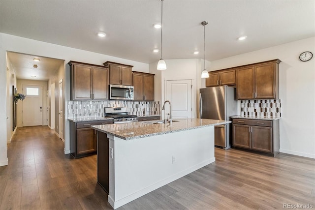 4992 Trails Edge Ln, Castle Rock, CO 80104 - kitchen with appliances with stainless steel finishes, a sink, dark wood finished floors, light stone countertops, and tasteful backsplash