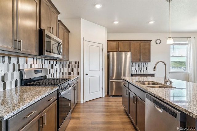 4992 Trails Edge Ln, Castle Rock, CO 80104 - kitchen with stainless steel appliances, a sink, dark wood-style floors, light stone countertops, and recessed lighting