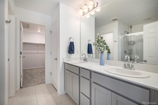 bathroom featuring tile patterned floors, a shower with door, and vanity