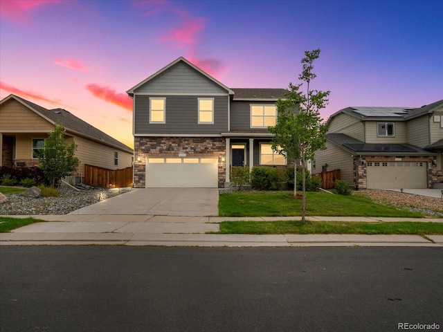 view of front of home with a garage, fence, concrete driveway, stone siding, and a front yard