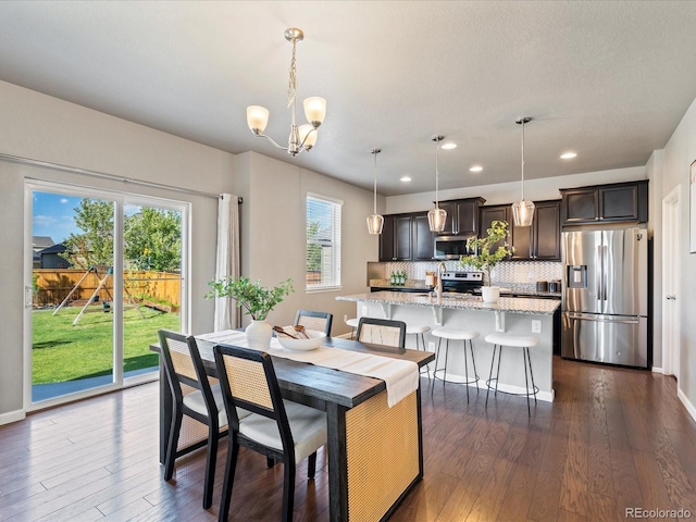 dining space featuring an inviting chandelier, plenty of natural light, and dark hardwood / wood-style flooring