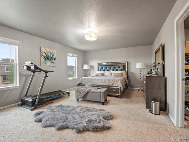 bedroom featuring multiple windows, light carpet, and a textured ceiling