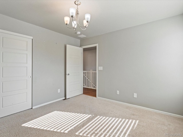 unfurnished bedroom with carpet flooring and a chandelier