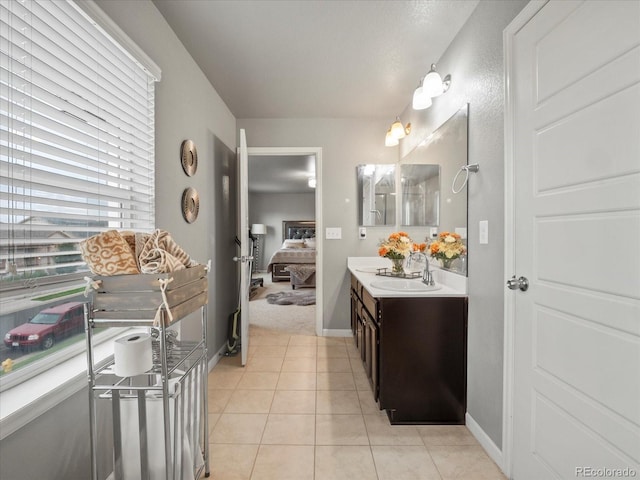 ensuite bathroom with tile patterned flooring, baseboards, vanity, and ensuite bath