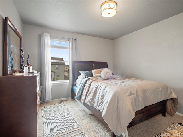 bedroom featuring light carpet and baseboards