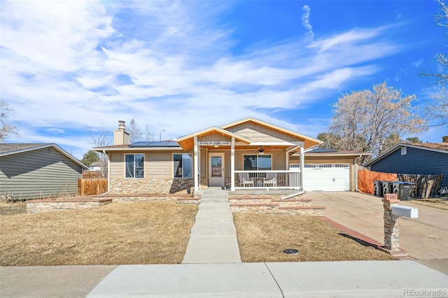 view of front of property with covered porch, ceiling fan, roof mounted solar panels, and fence