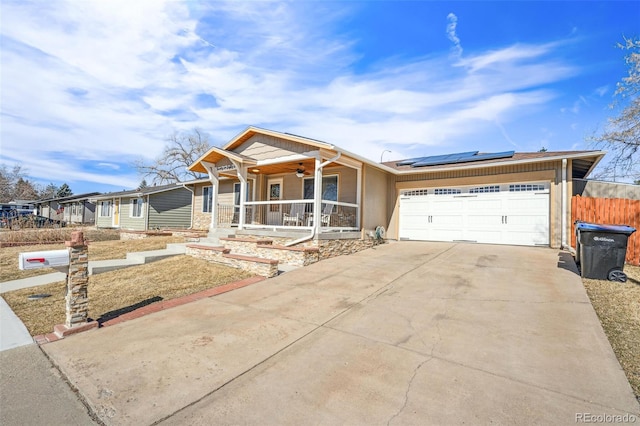 view of front facade with solar panels, covered porch, concrete driveway, an attached garage, and ceiling fan