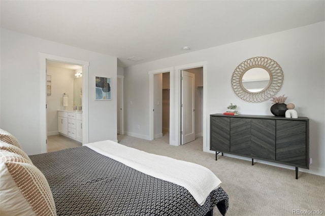 bedroom featuring light colored carpet, connected bathroom, and a spacious closet