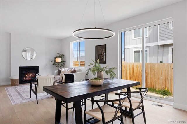 4018 Upham St, Wheat Ridge, CO 80033 - dining space featuring visible vents, light wood-style flooring, baseboards, and a glass covered fireplace
