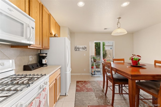 kitchen featuring hanging light fixtures, backsplash, a textured ceiling, white appliances, and light tile patterned flooring