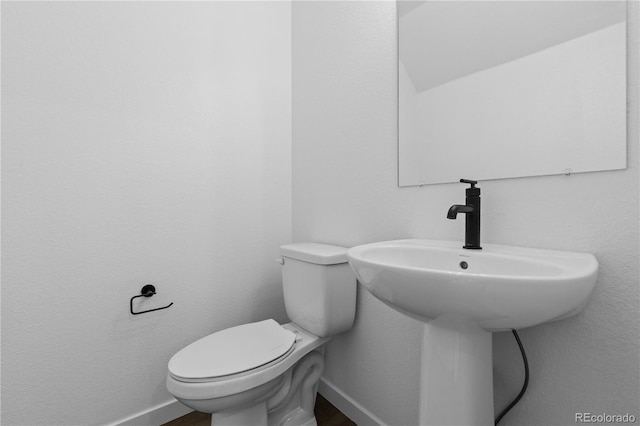 half bathroom with toilet, baseboards, and wood finished floors