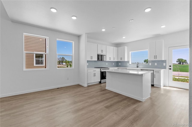 kitchen featuring appliances with stainless steel finishes, light countertops, tasteful backsplash, white cabinetry, and light wood-style floors