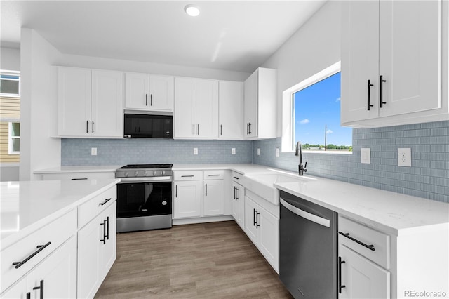 kitchen featuring appliances with stainless steel finishes, a sink, white cabinetry, backsplash, and recessed lighting