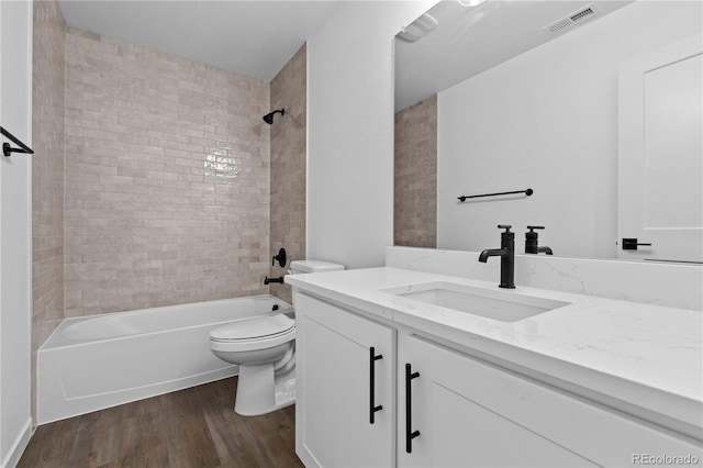 full bath with toilet, wood finished floors, vanity, and shower / bath combination