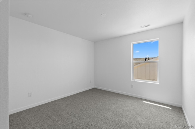 carpeted empty room with a smoke detector and baseboards