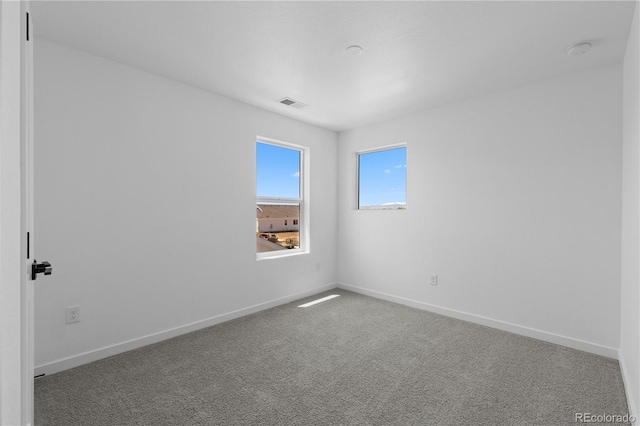 carpeted empty room featuring baseboards and a smoke detector