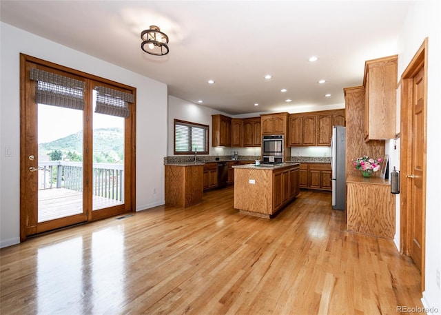 1660 Old Antlers Way, Monument, CO 80132 - kitchen featuring freestanding refrigerator, a center island, brown cabinetry, light wood-style flooring, and recessed lighting