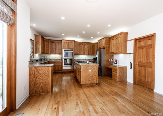 1660 Old Antlers Way, Monument, CO 80132 - kitchen with appliances with stainless steel finishes, a center island, light wood-style floors, brown cabinets, and recessed lighting