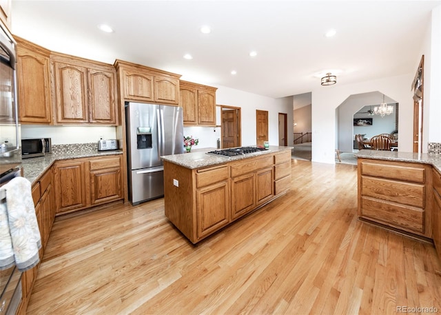1660 Old Antlers Way, Monument, CO 80132 - kitchen featuring stainless steel appliances, a kitchen island, light wood-style floors, arched walkways, and a chandelier