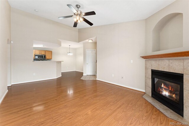 7440 S Blackhawk St Unit 7-303, Englewood, CO 80112 - unfurnished living room featuring a tiled fireplace, wood finished floors, baseboards, and ceiling fan