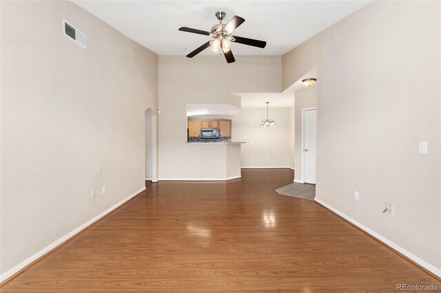 7440 S Blackhawk St Unit 7-303, Englewood, CO 80112 - unfurnished living room with a ceiling fan, arched walkways, baseboards, wood finished floors, and a high ceiling