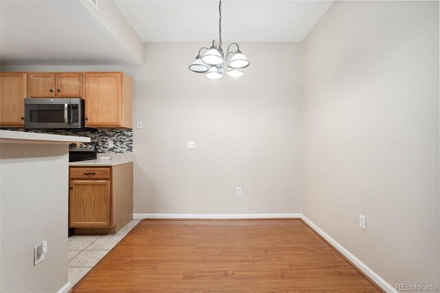 7440 S Blackhawk St Unit 7-303, Englewood, CO 80112 - kitchen with stainless steel microwave, a chandelier, tasteful backsplash, light wood-type flooring, and hanging light fixtures