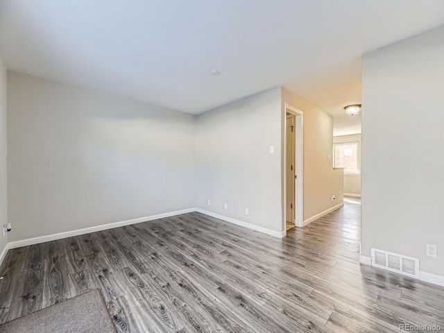 spare room with visible vents, baseboards, and wood finished floors