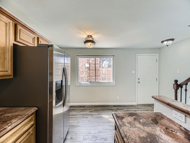 kitchen featuring wood finished floors, brown cabinetry, stainless steel fridge with ice dispenser, and baseboards