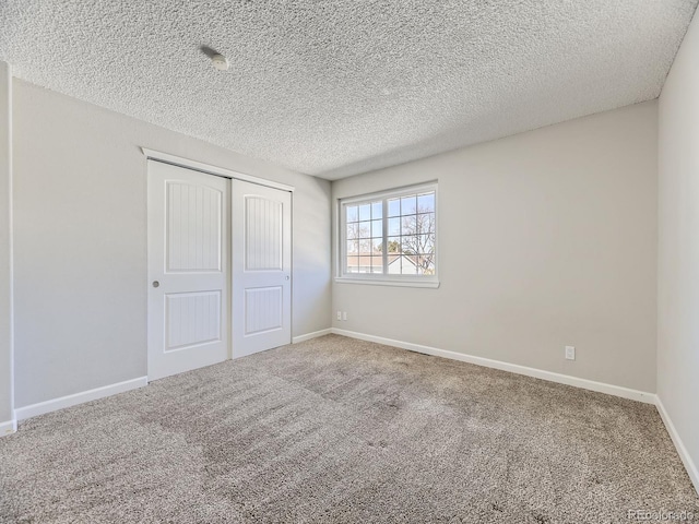 unfurnished bedroom featuring a textured ceiling, carpet, a closet, and baseboards