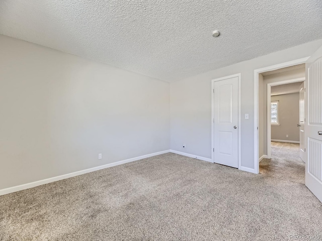 empty room featuring baseboards, carpet floors, and a textured ceiling