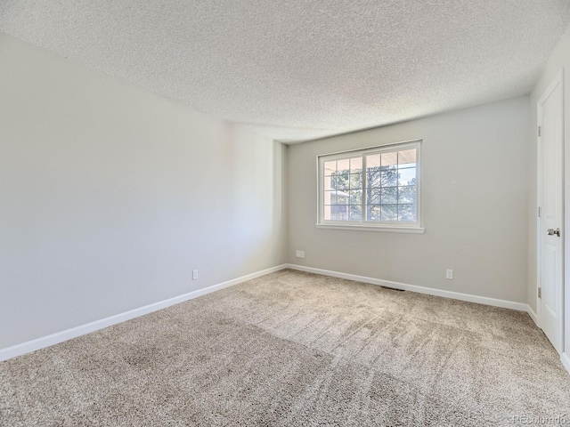 empty room with carpet flooring, baseboards, and a textured ceiling