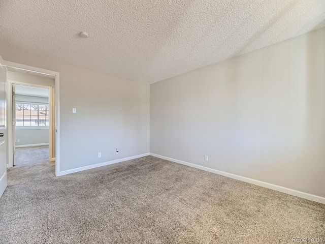 spare room featuring baseboards, a textured ceiling, and carpet flooring