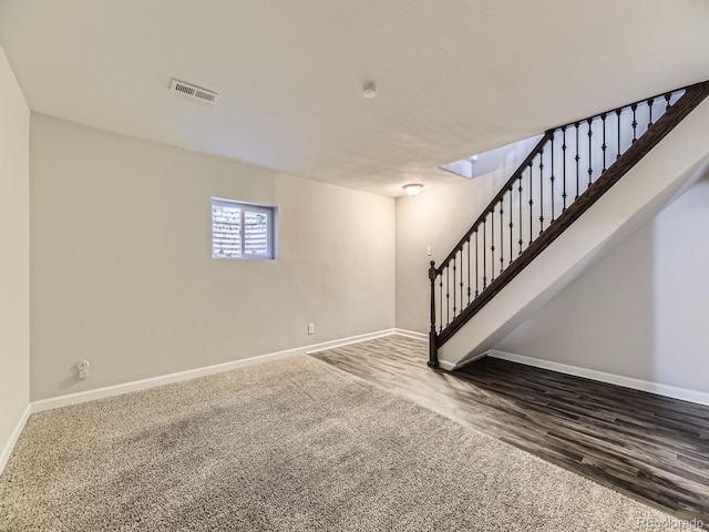 below grade area featuring wood finished floors, stairway, baseboards, and visible vents