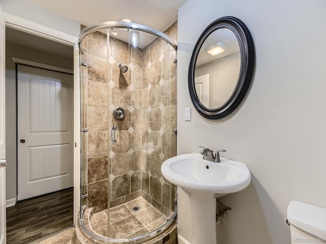 full bathroom featuring toilet, wood finished floors, and a shower stall