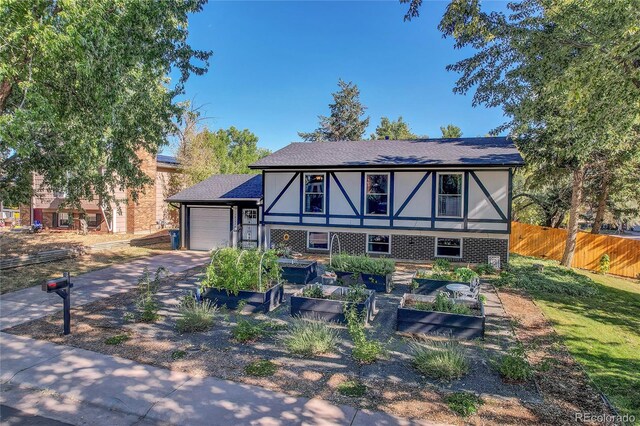 view of front of house featuring brick siding, concrete driveway, fence, a garage, and a garden