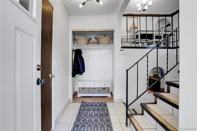 mudroom with light tile patterned flooring, an inviting chandelier, and a textured ceiling