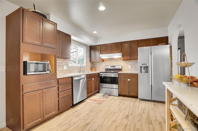 kitchen with stainless steel appliances, recessed lighting, decorative backsplash, light wood-style floors, and under cabinet range hood