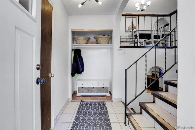 mudroom featuring an inviting chandelier, light tile patterned floors, and a textured ceiling